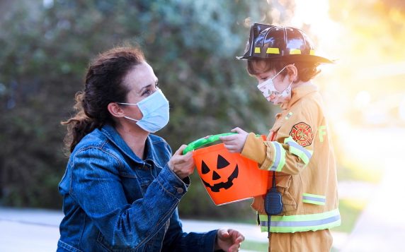 Mature woman and a child boy wearing protective face masks before going to ask trick or treat halloween