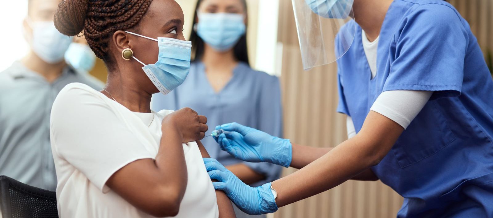 Woman administers a COVID vaccine to another woman.