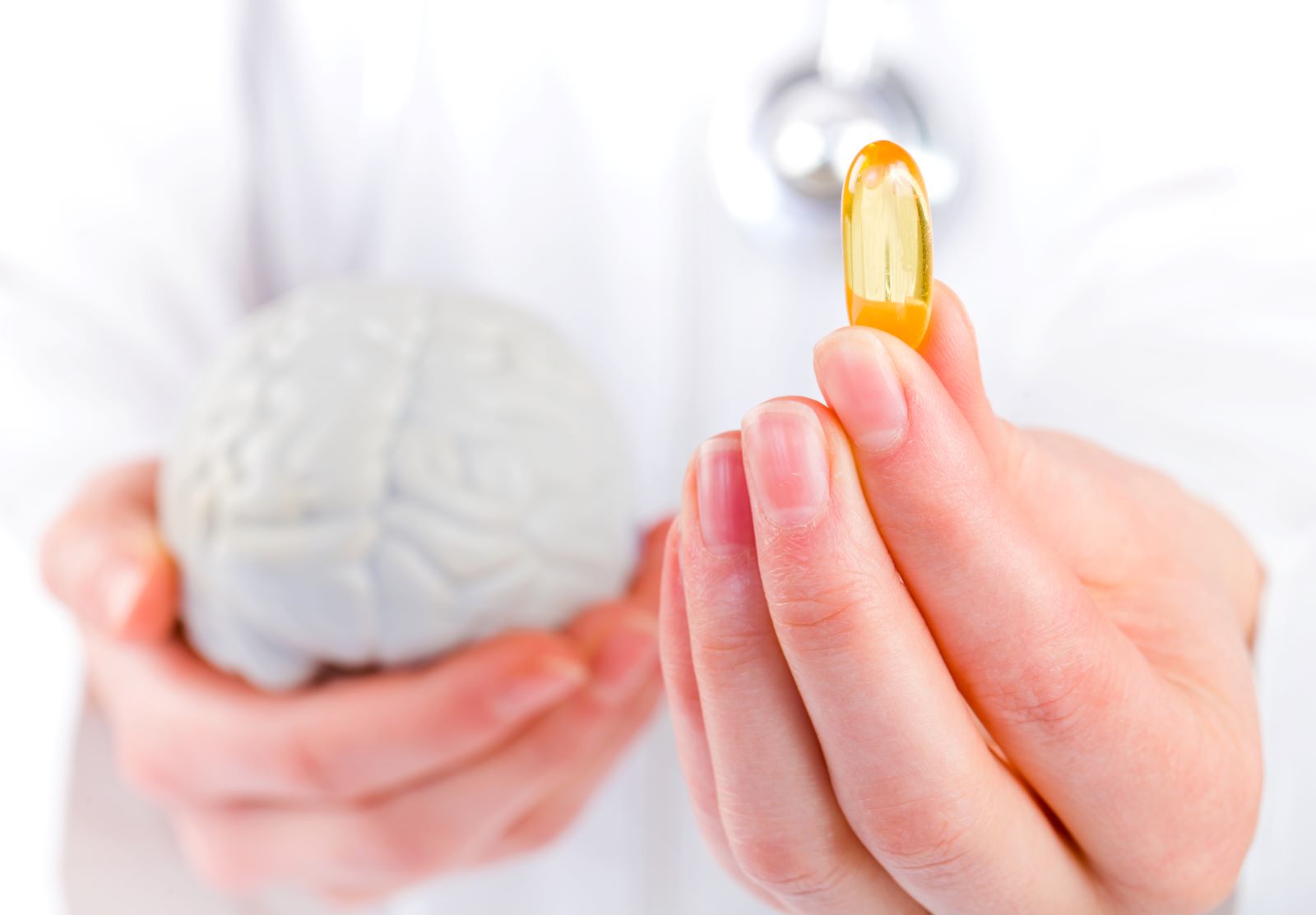 Person holding a model of the brain and a brain supplement.