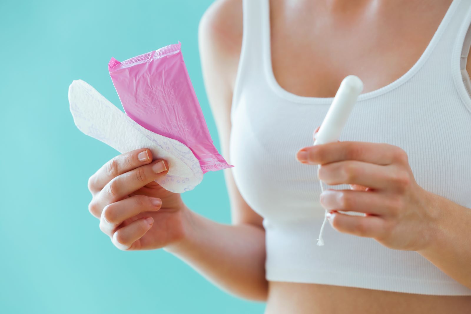 Woman holding a tampon and pad.
