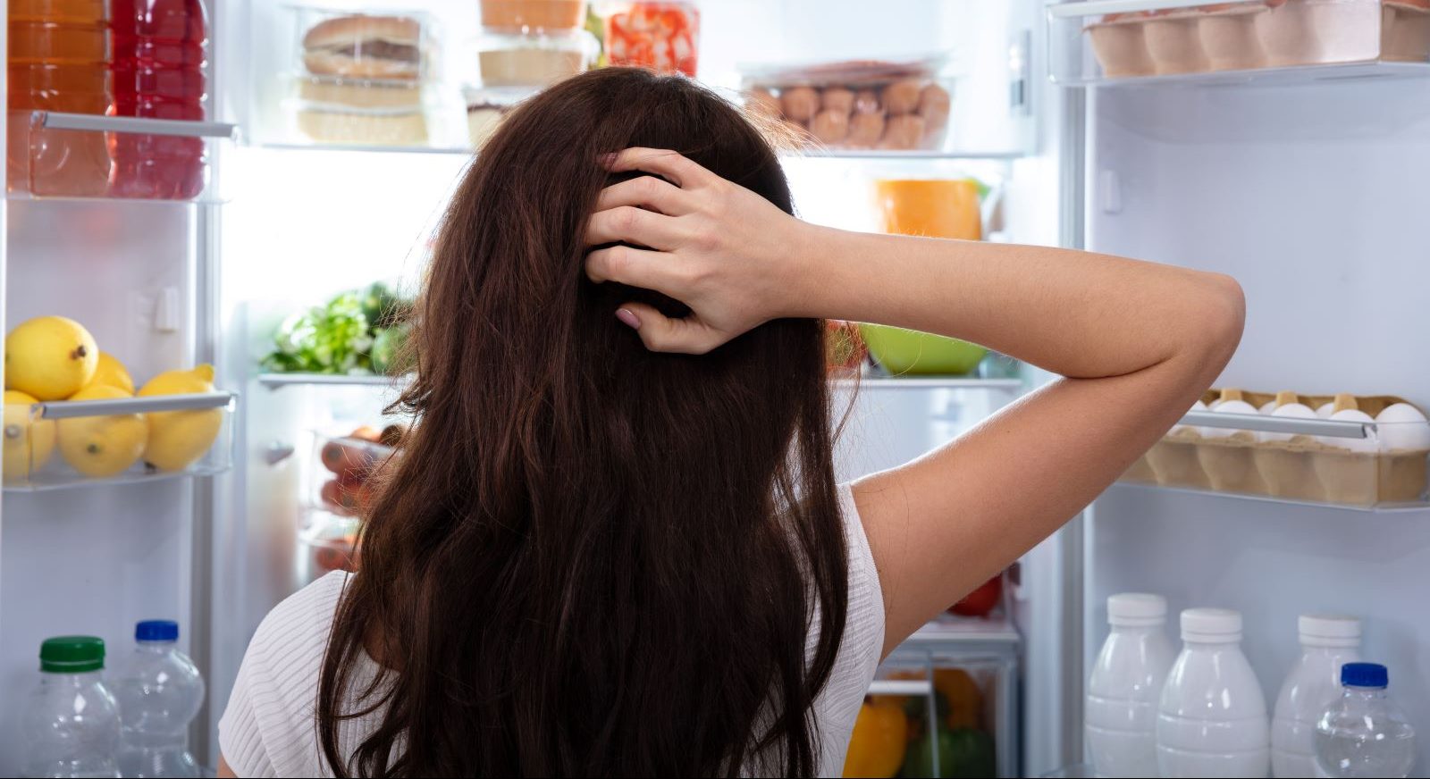 A person looks for food in the fridge.